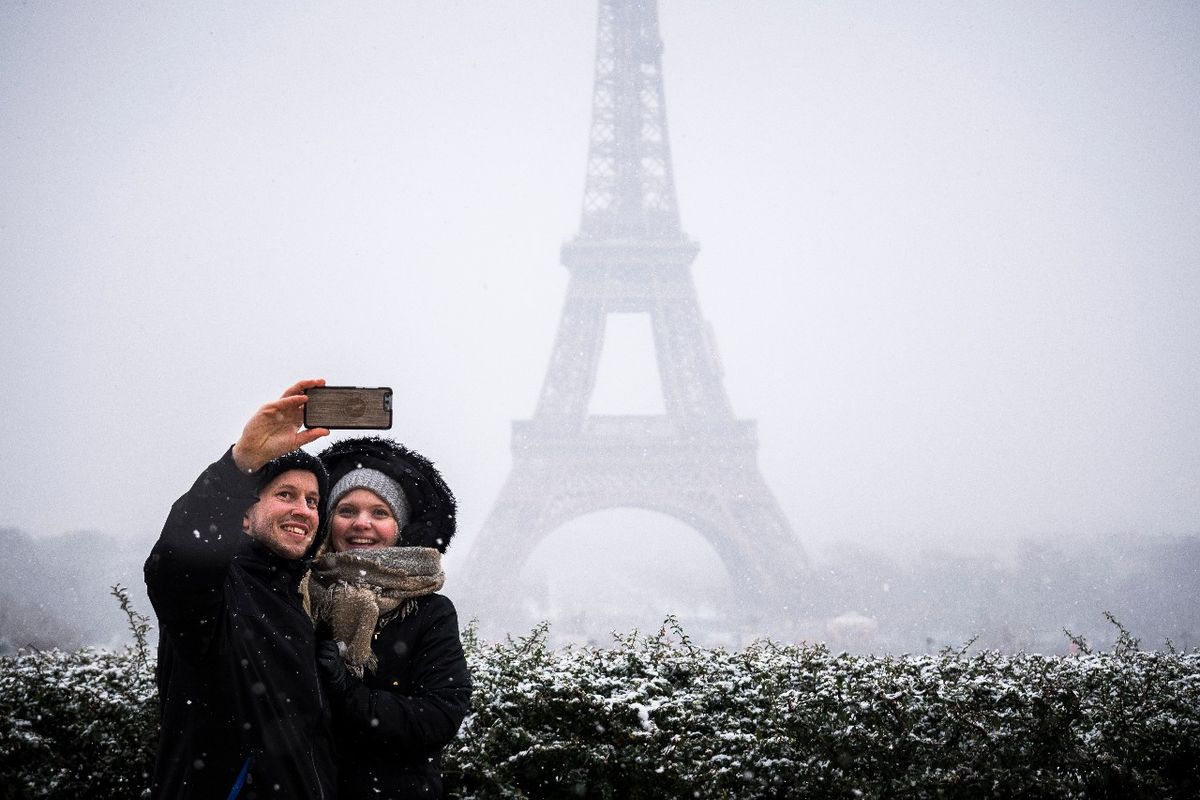 Una pareja posa para una selfie bajo la nieve en la Place du Trocadero frente a la Torre Eiffel en París el 5 de febrero de 2018. / PH: Lionel BONAVENTURE - AFP.