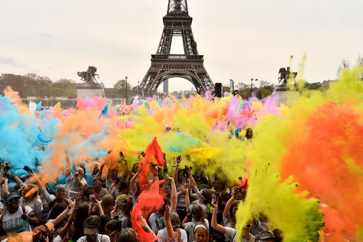 Los corredores celebran bajo polvo de color terminando sus cinco kilómetros en el Color Run 2018 en la Torre Eiffel en París el 15 de abril de 2018. / PH: Christophe Simon - AFP.